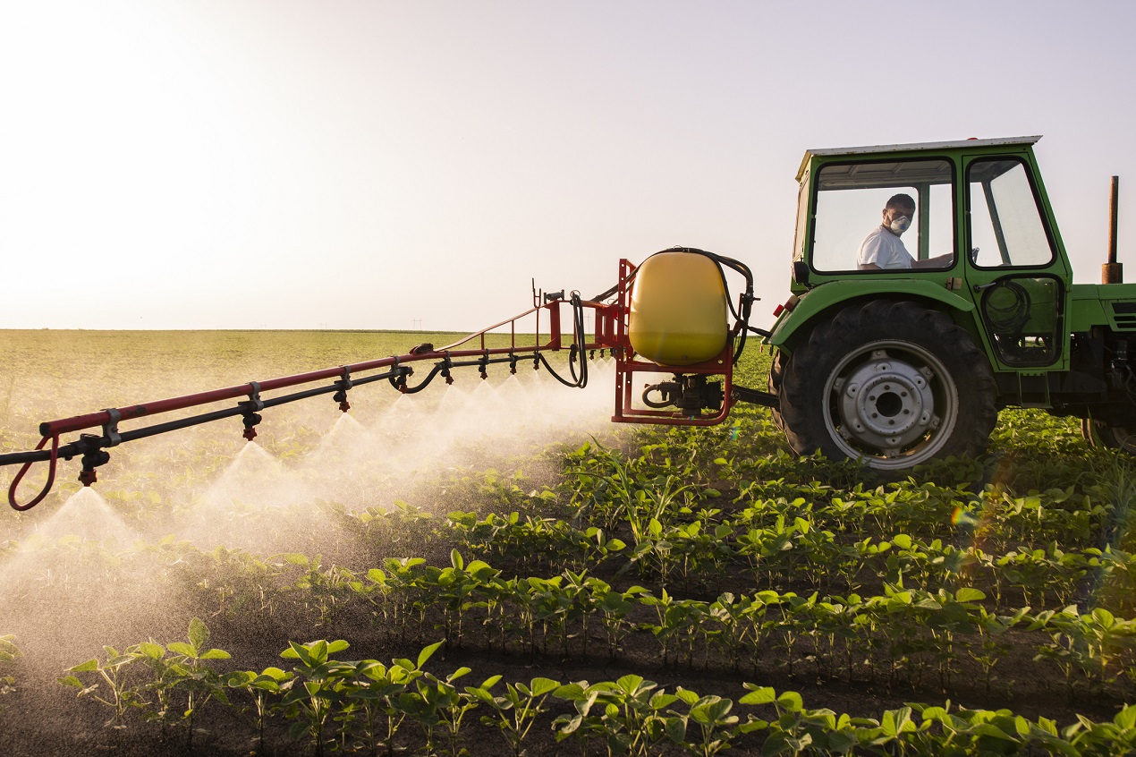 Mężczyzna w traktorze spryskuje glebe azotem dla lepszych plonów