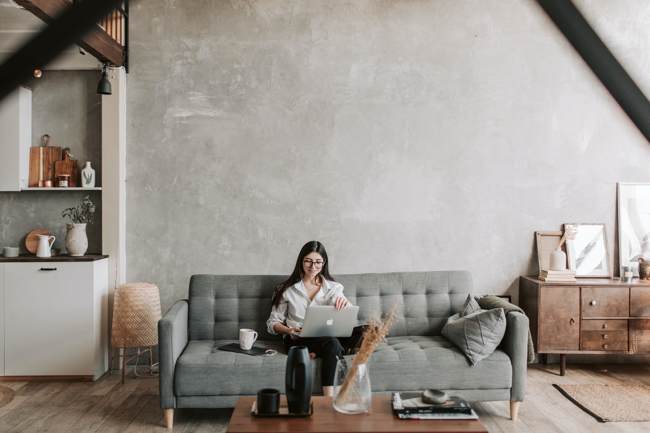 kobieta siedząca z laptopem na dużej sofie