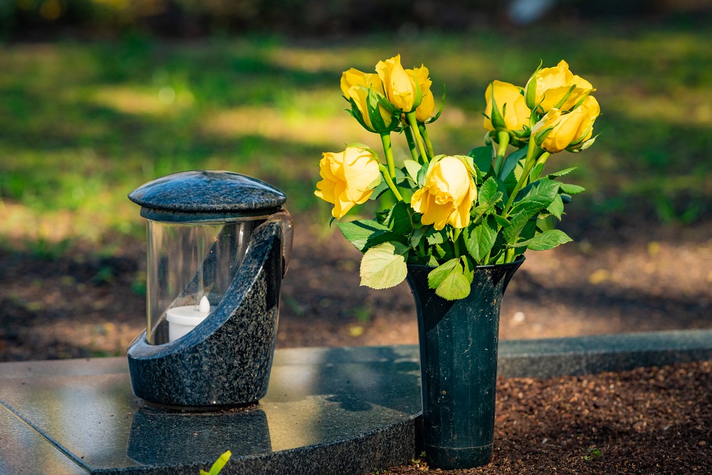 Kwiaty stoją w wazonie na nagrobku na cmentarzu