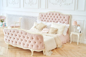 Duże, zadbane, różowe tapicerowane łóżko w sypialni