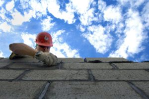 Mężczyzna używa bloczków z betonu komórkowego przy budowie