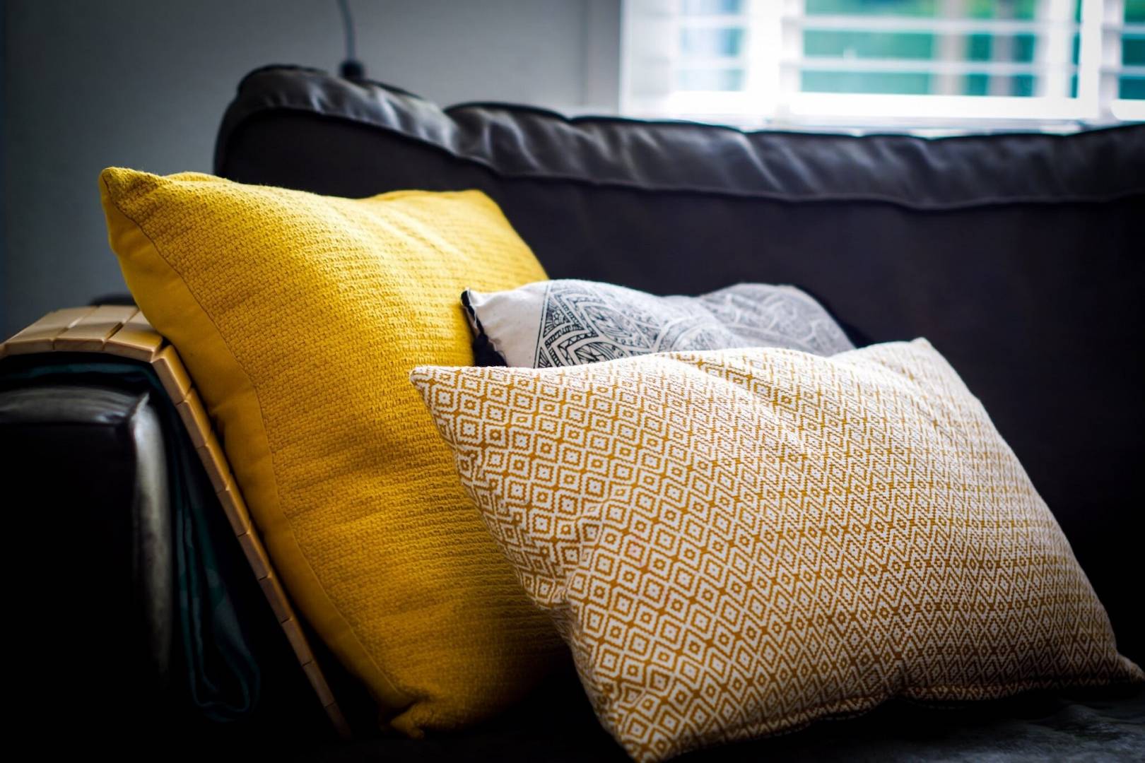 Kolorowe poduszki leżą na ciemnej kanapiel