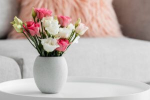 Bukiet ze sztucznych kwiatów w wazonie stoi na białym stoliku w salonie