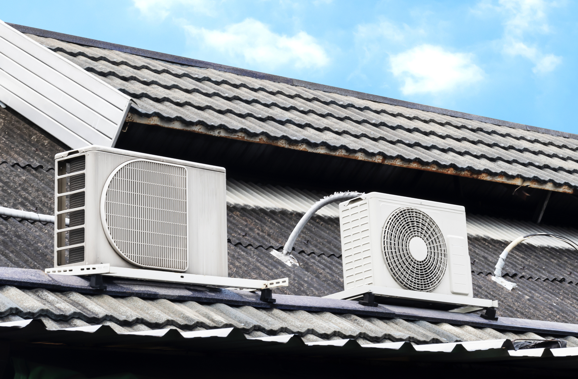 Na obrazku możemy zobaczyć białe klimatyzatory typu multi split zamontowane na dachu domu. Urządzenia te służą do klimatyzacji pomieszczeń wewnątrz budynku. Montaż na dachu pozwala na wykorzystanie miejsca na zewnątrz, co jest szczególnie ważne w przypadku mniejszych działek. Dzięki temu rozwiązaniu, klimatyzatory nie zajmują cennego miejsca wewnątrz domu i pozwalają na skuteczną regulację temperatury w każdym pomieszczeniu.