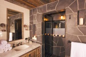 Na tym ujmującym obrazku możemy podziwiać urokliwą rustykalną łazienkę, gdzie naturalne elementy i rustykalne detale tworzą wyjątkową atmosferę. Drewniane belki sufitowe, podłoga z kamienia oraz rustykalne meble nadają pomieszczeniu ciepło i charakter. Styl rustykalny łazienki emanuje spokojem i przyjemnością, zapewniając idealne miejsce do relaksu i odprężenia