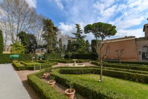 Na zdjęciu widoczny jest uroczy włoski ogród, który oczarowuje swoją piękną kompozycją. Roślinność w stylu śródziemnomorskim, charakterystyczne elementy architektoniczne i gładko przycięte żywopłoty tworzą harmonijną scenerię. Wodne fontanny i malownicze alejki dodają temu ogrodowi włoskiemu niepowtarzalnego uroku i romantycznego nastroju