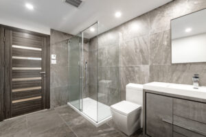 Na tym zachwycającym obrazku możemy podziwiać szarą, nowoczesną łazienkę z prysznicem. Kolorystyka dominująca w pomieszczeniu nadaje mu elegancji i minimalistycznego charakteru. Przestronny prysznic o nowoczesnym designie stanowi centralny punkt tej łazienki, tworząc harmonijną i funkcjonalną przestrzeń kąpielową