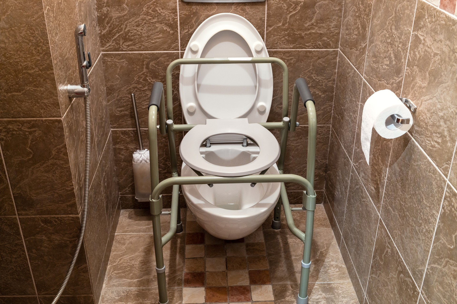 Na obrazku możemy zobaczyć specjalnie dostosowaną toaletę dla osób niepełnosprawnych. Toaleta posiada podwyższone siedzisko, ułatwiające korzystanie osobom z ograniczoną mobilnością. Dodatkowo, widoczne są poręcze przy toalecie, które zapewniają dodatkowe wsparcie i bezpieczeństwo podczas korzystania z niej. Projekt toalety dla niepełnosprawnych uwzględnia ich specyficzne potrzeby, zapewniając komfort i dostępność dla wszystkich użytkowników