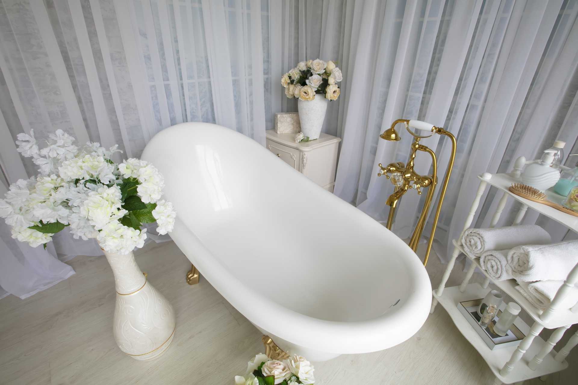 Ten wspaniały obrazek przedstawia białą łazienkę w stylu biało złotym, która emanuje pięknem i elegancją. Ściany pokryte jasnymi płytkami nadają wnętrzu czystość i przestronność, tworząc harmonijną atmosferę relaksu. Złote akcenty, takie jak kraniki i dodatki, dodają tej łazience wyjątkowego blasku i luksusowego charakteru, sprawiając, że jest to miejsce pełne przepychu i stylu