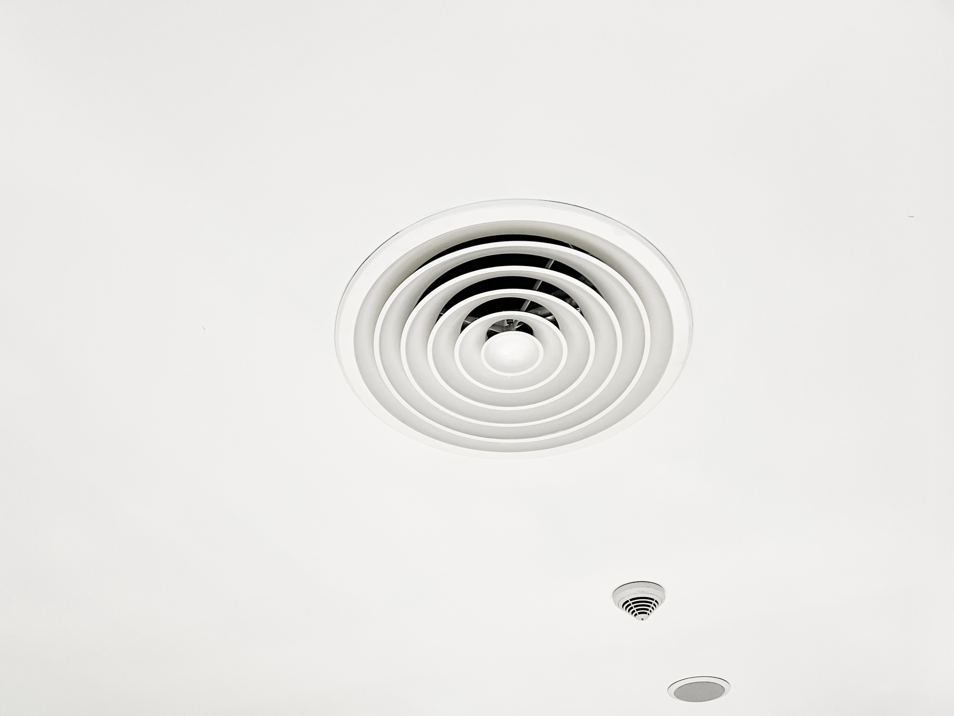 Na obrazku widać biały łazienkowy wentylator, który harmonijnie komponuje się z wnętrzem, nadając mu nowoczesny i elegancki wygląd. Jego minimalistyczny design doskonale pasuje do czystej i świeżej estetyki łazienki. Ten obrazek prezentuje funkcjonalność i styl, jakie może dodać biały wentylator do łazienki, zapewniając jednocześnie efektywną wentylację i usuwanie wilgoci